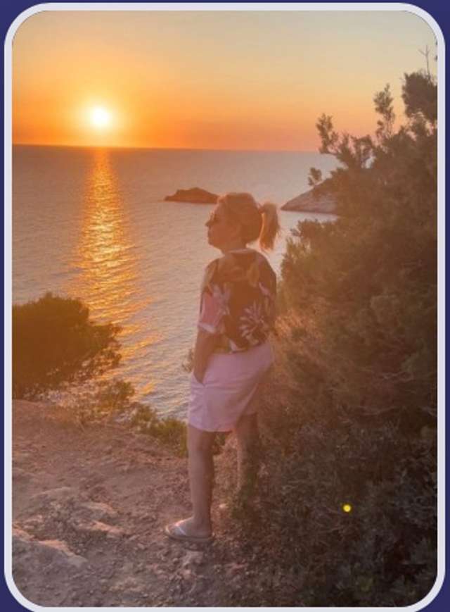 Maria Camilo observando o pôr do sol à beira-mar